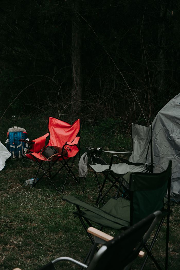 Chairs and tent in a forest campsite, ideal for outdoor enthusiasts seeking nature adventures.